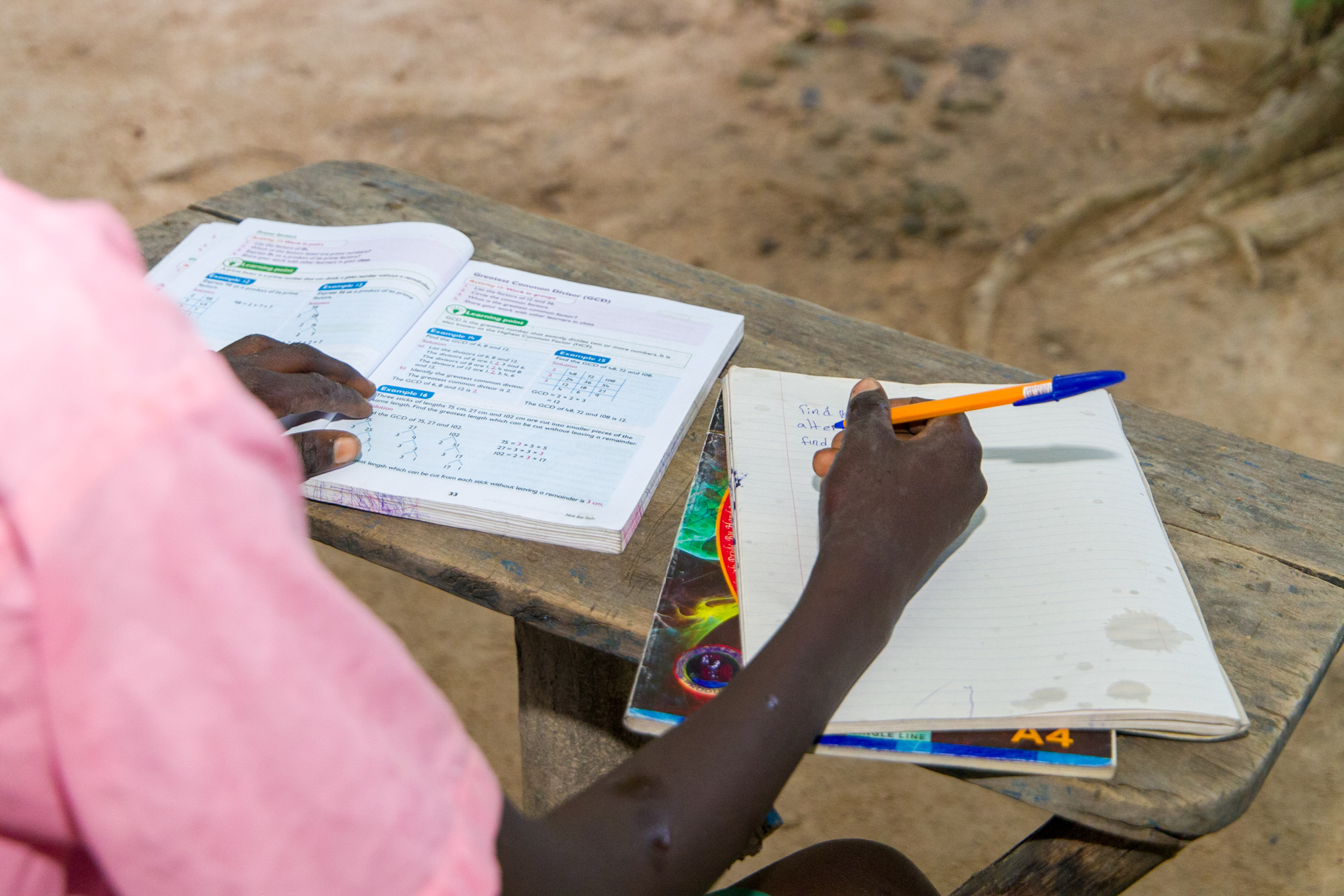 Charang writing down notes as he reads from a textbook.