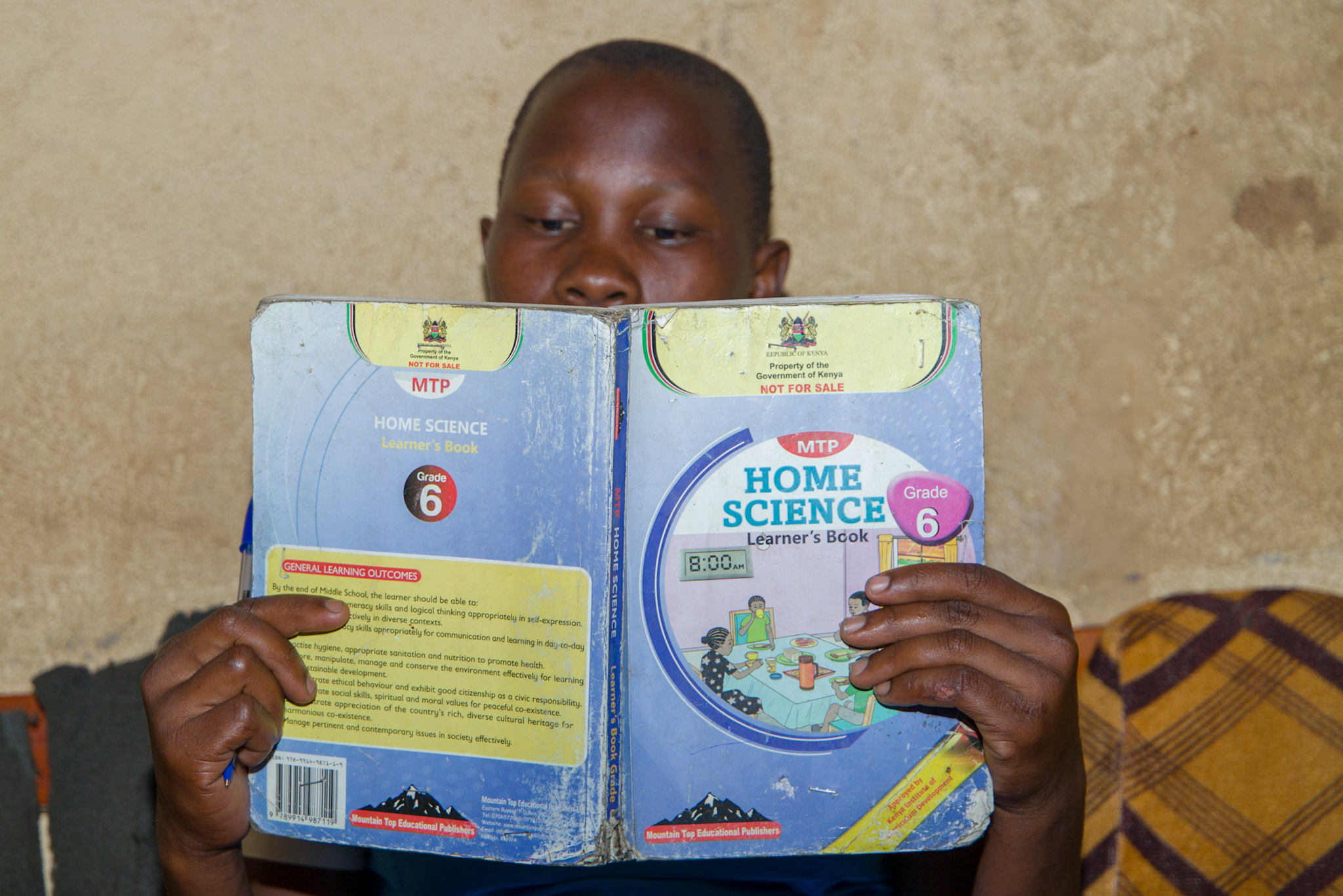 Rembo* reading a book inside her home.