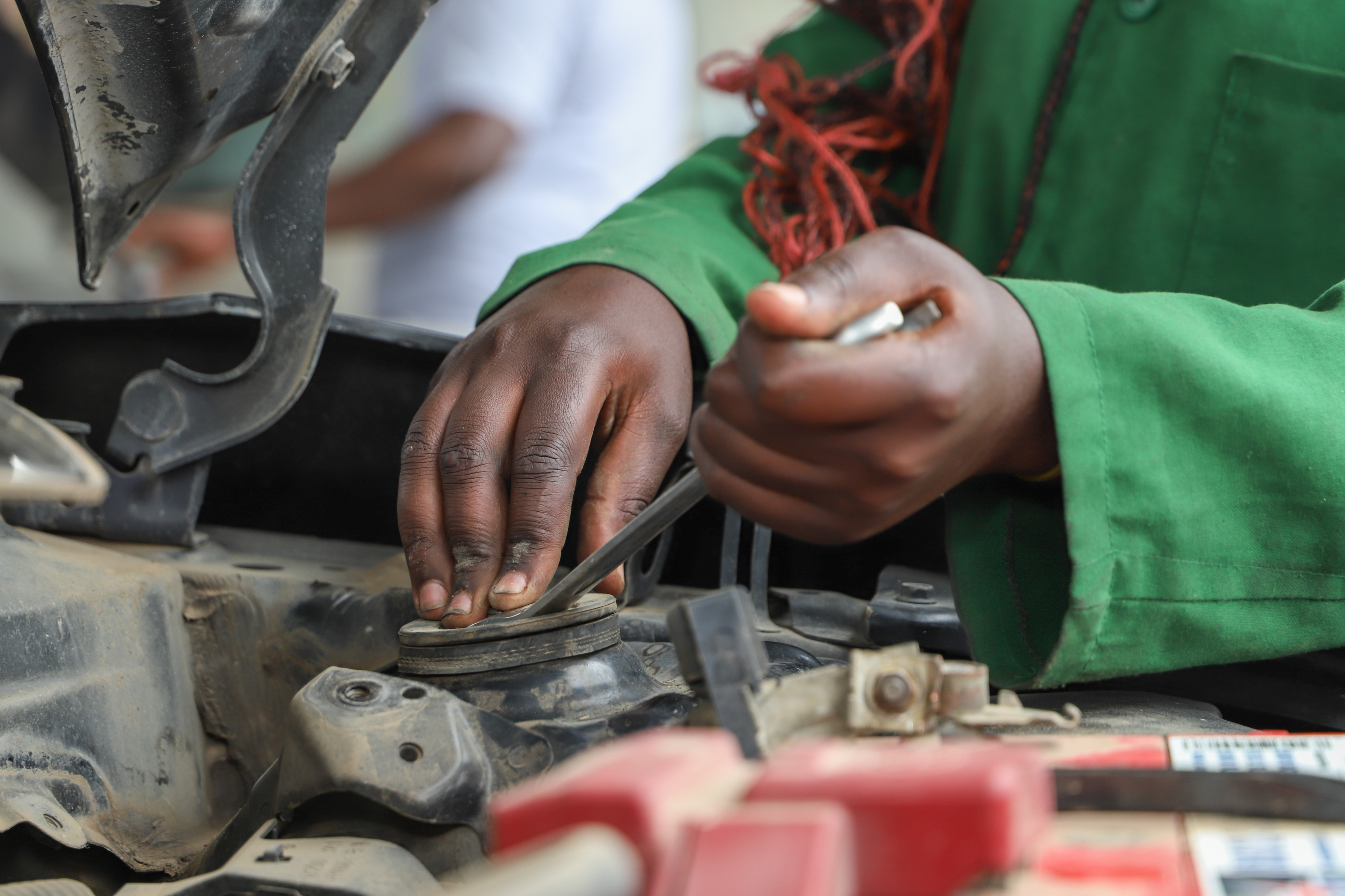 Mama county loosening a screw as she begins repairing a car.