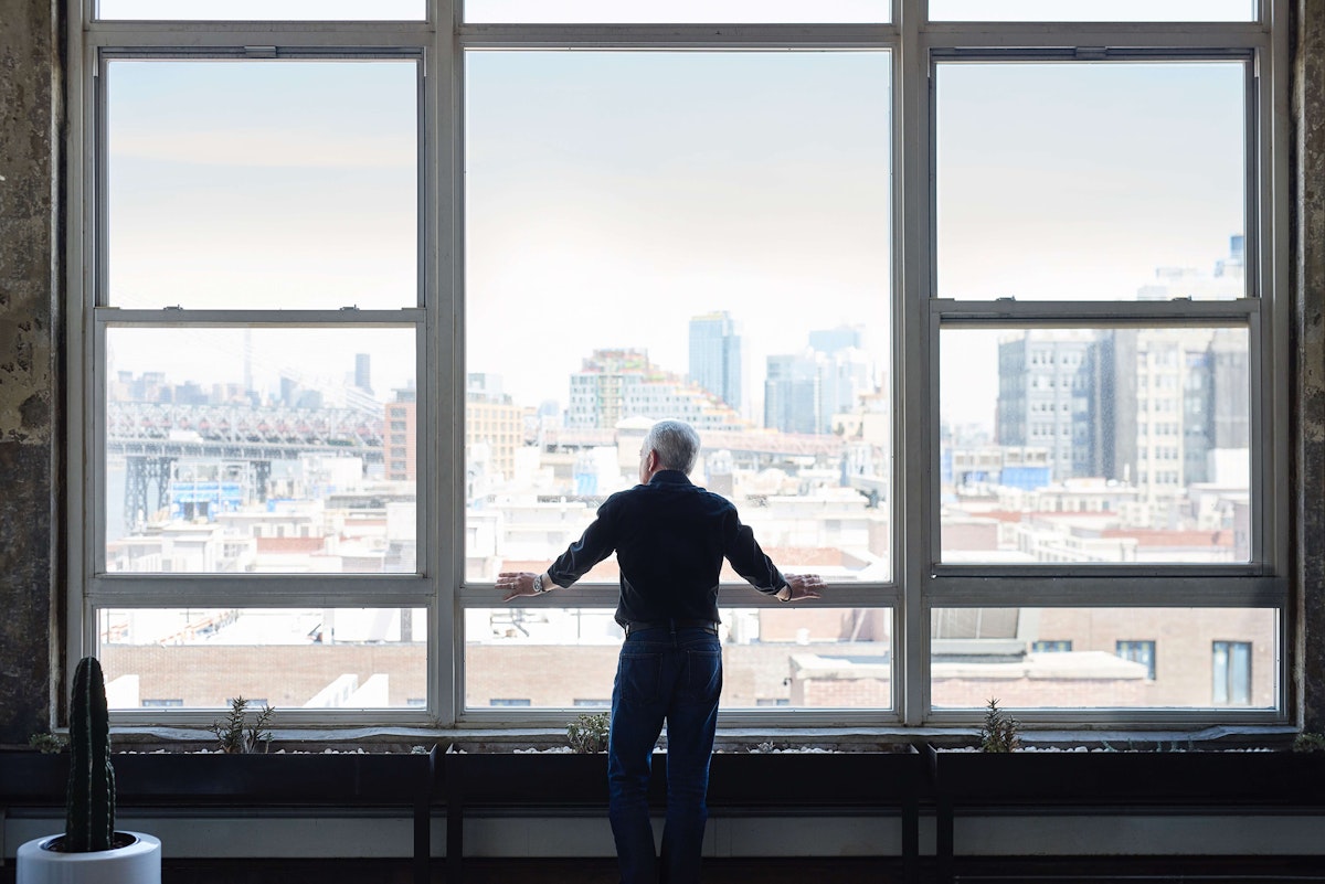 Carlos Vinãls looking out a large window at a sprawling cityscape