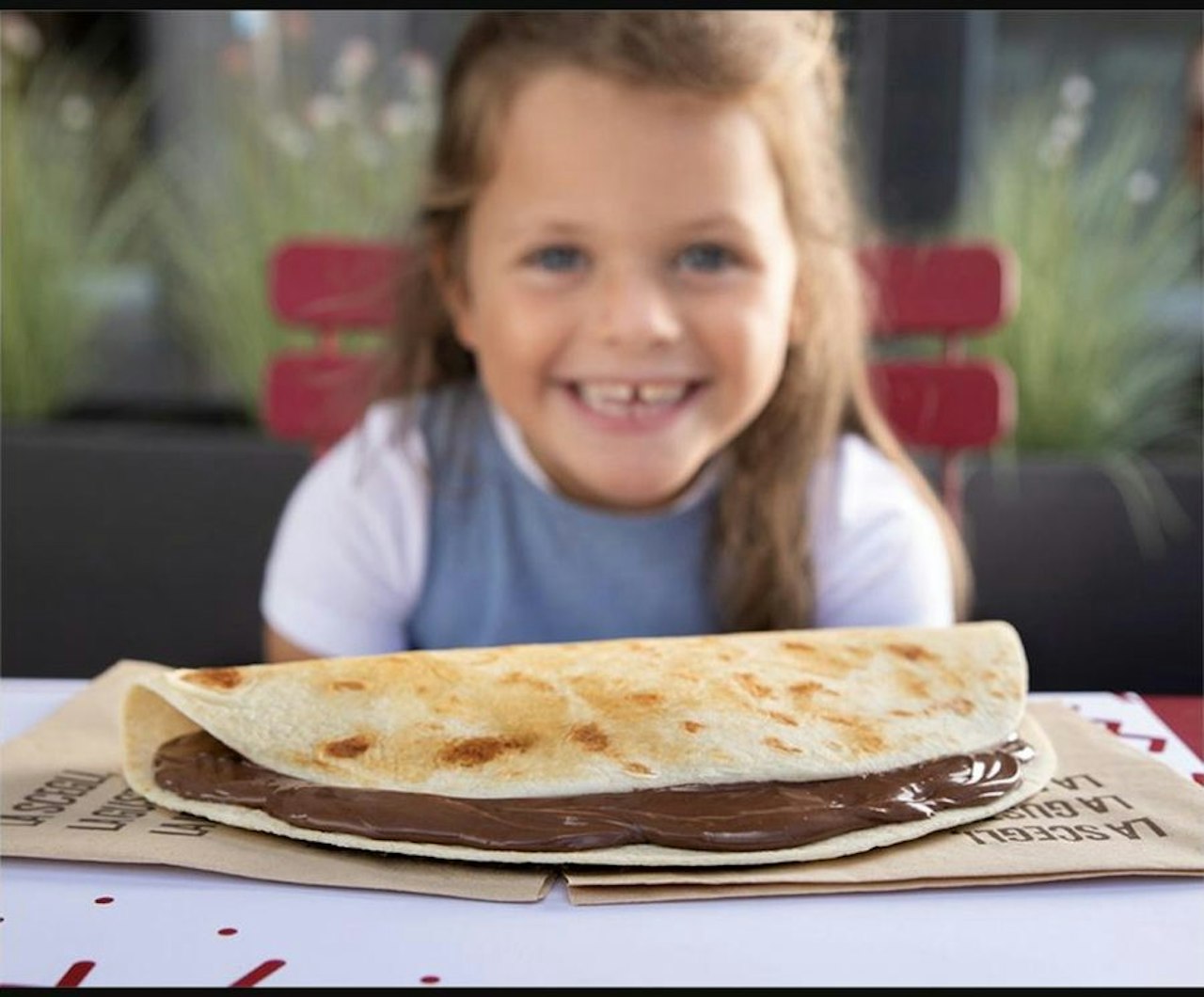 A child smiling behind a freshly folded piadina