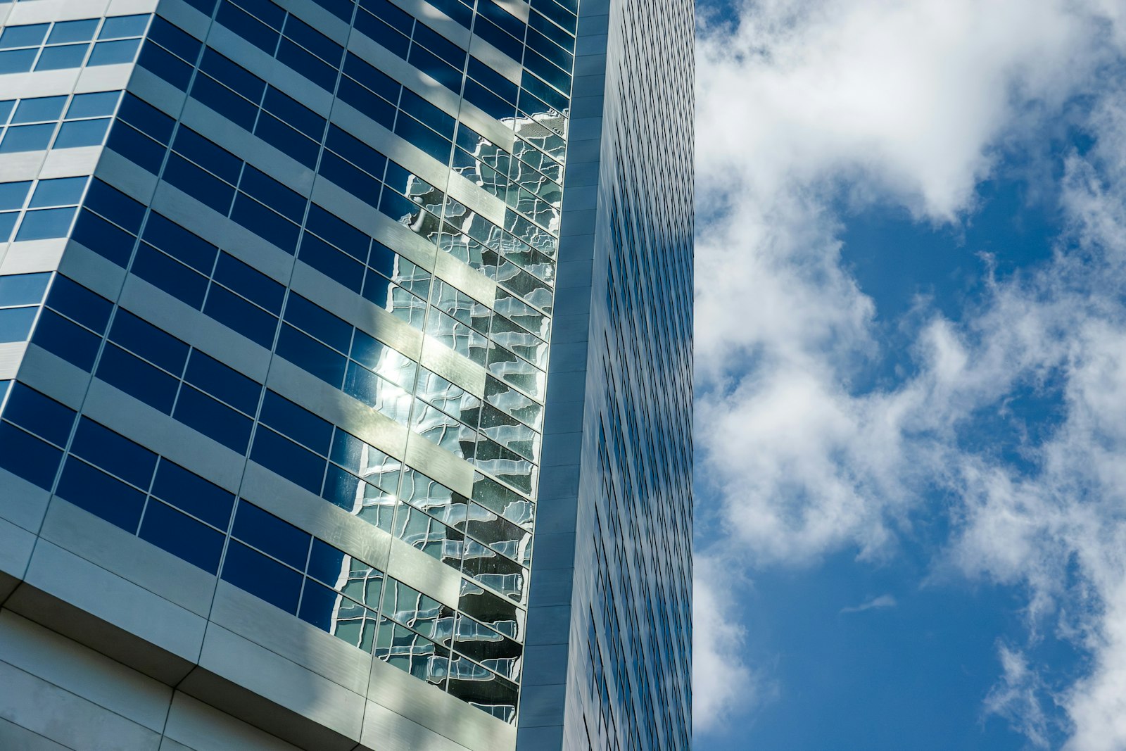 Sunlight and cloud reflected in a glass office tower.