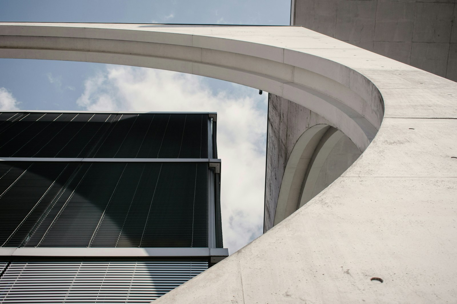 Modern office building facade combining curved concrete and glass.