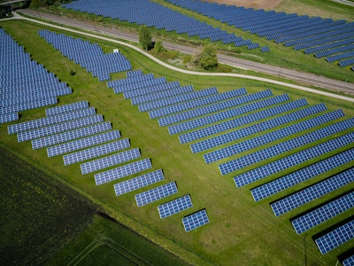 Aerial photography of grass field with blue solar panels.