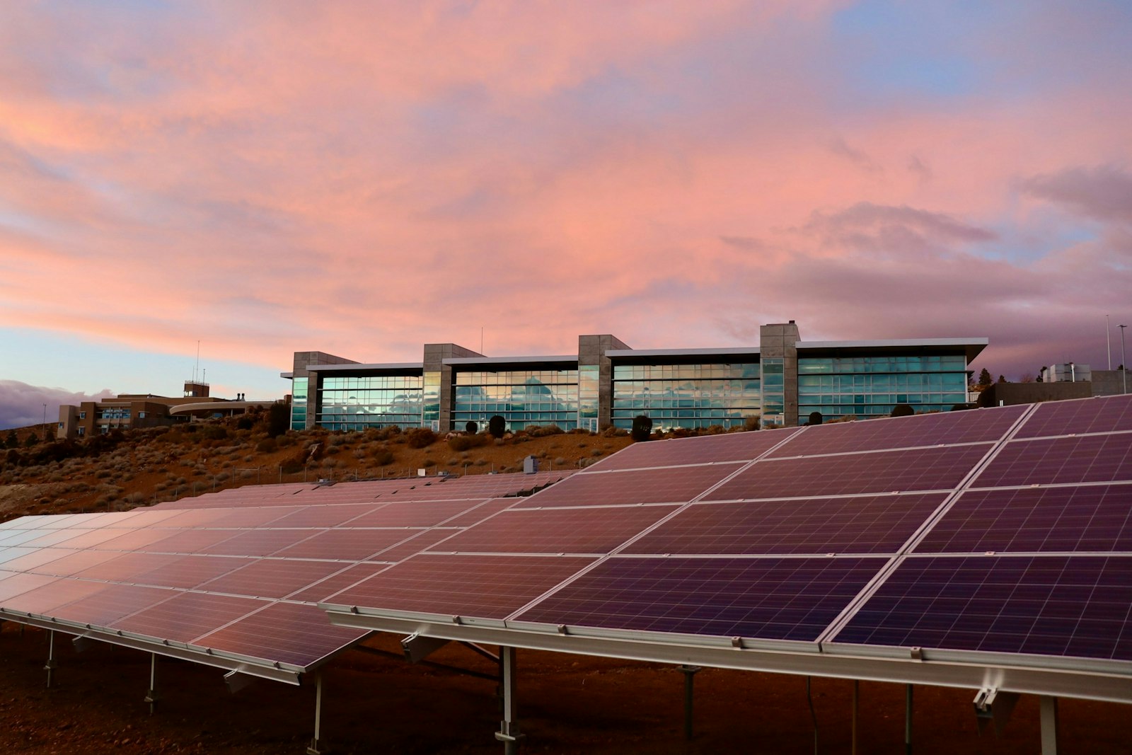 Solar panels on brown field under white clouds during daytime.