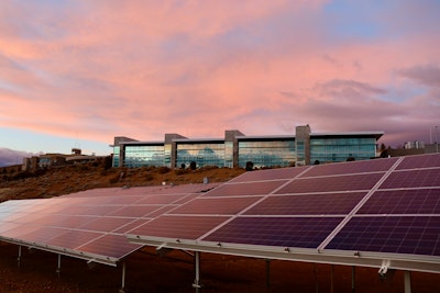 Solar panels on brown field under white clouds during daytime.