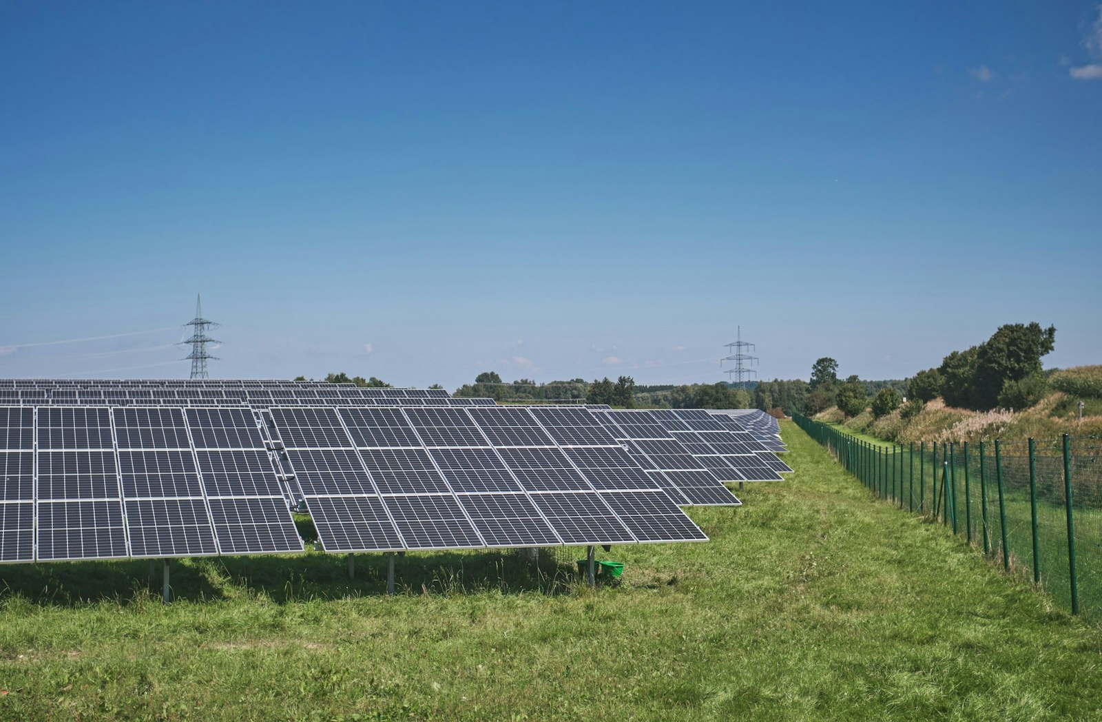 Solar panels on green grass field under blue sky during daytime.