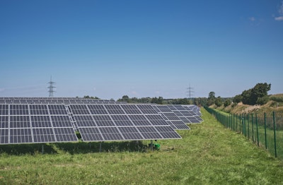 Solar panels on green grass field under blue sky during daytime.