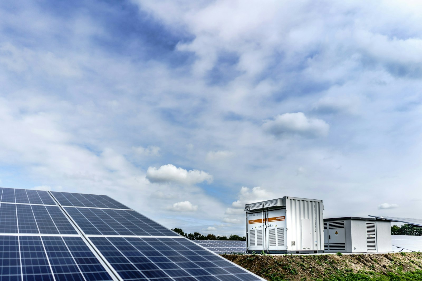 White and black solar panels under white clouds and blue sky during daytime.