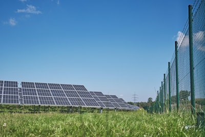 Solar panels on green grass field under blue sky during daytime.