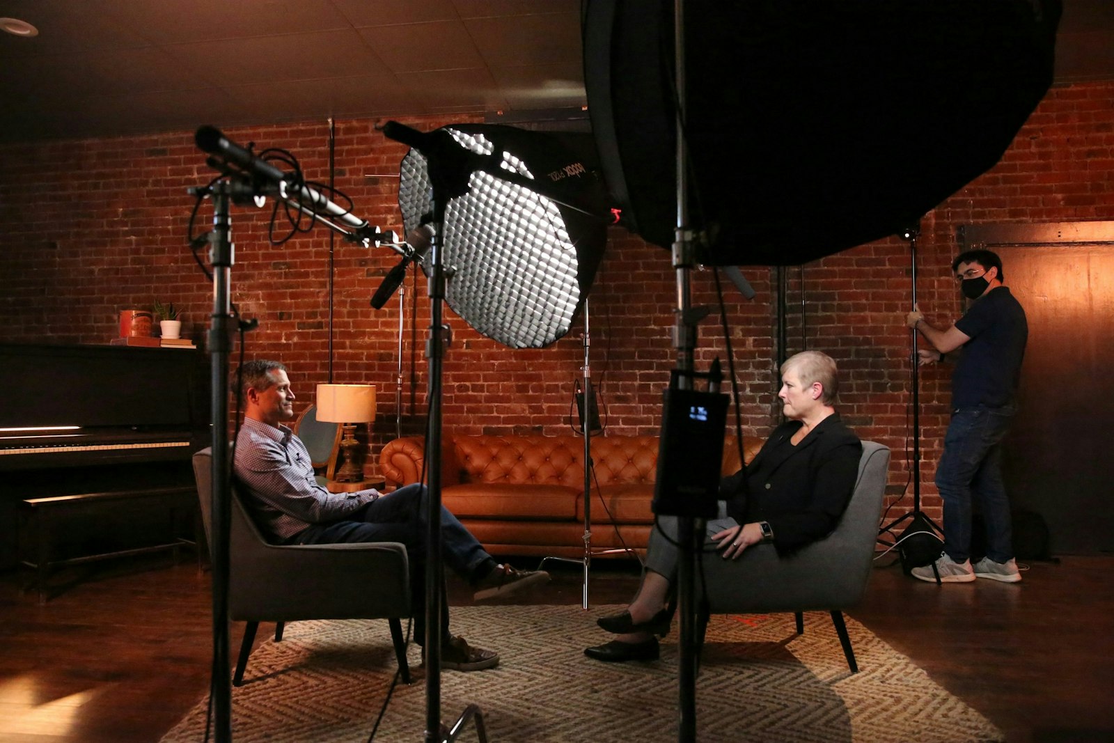 A man and a woman sitting in chairs in front of a camera.