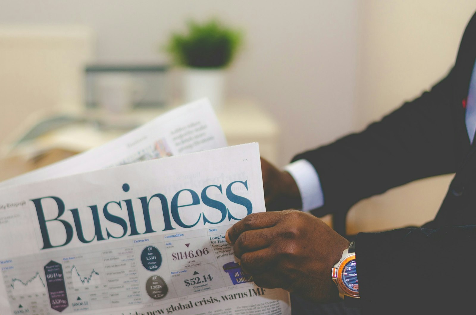 Person wearing suit reading business newspaper.