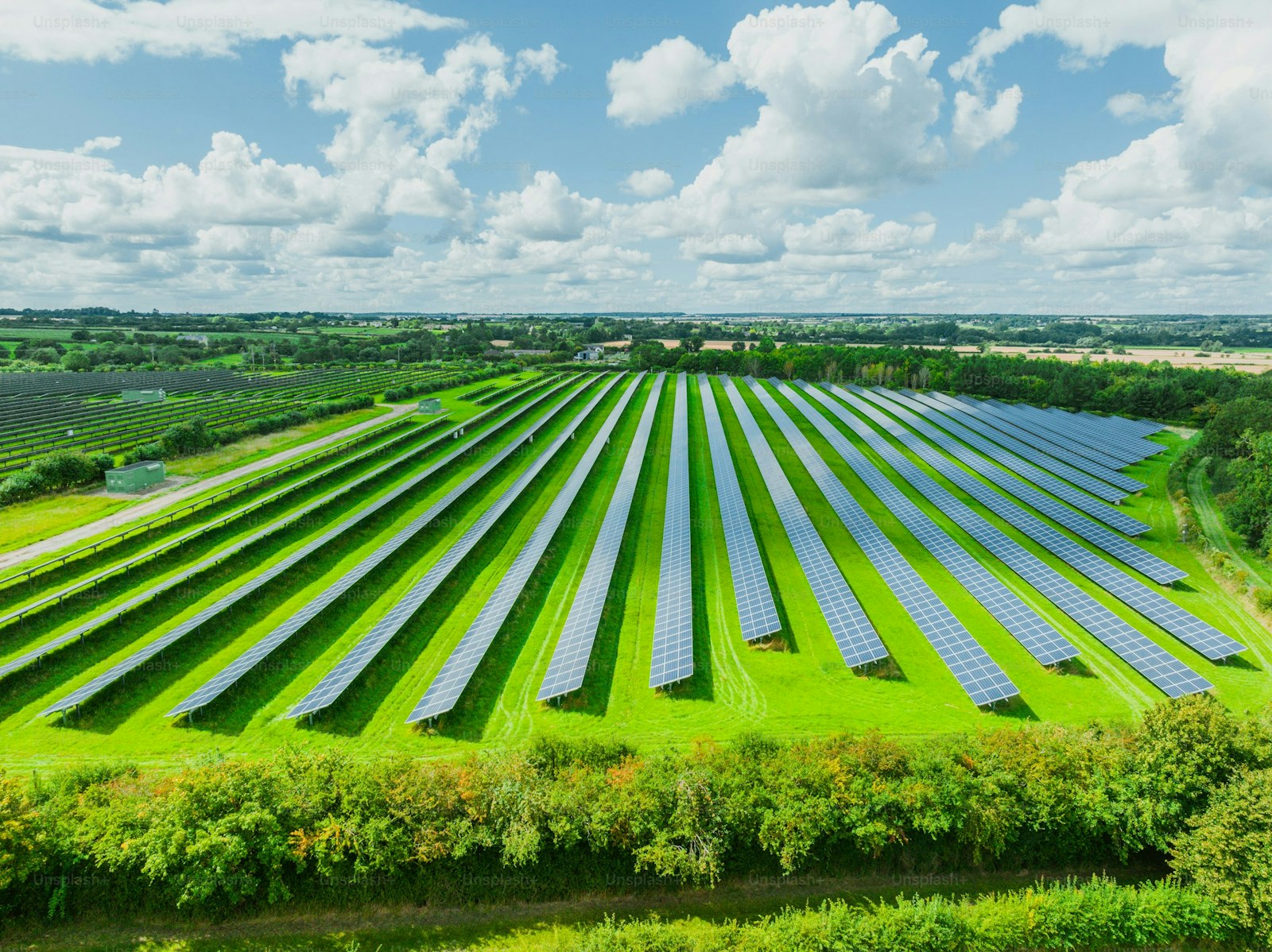 Aerial view of solar panels on green field at suburb in sunny day.