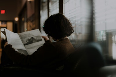 Woman in brown long sleeve shirt sitting by the window.