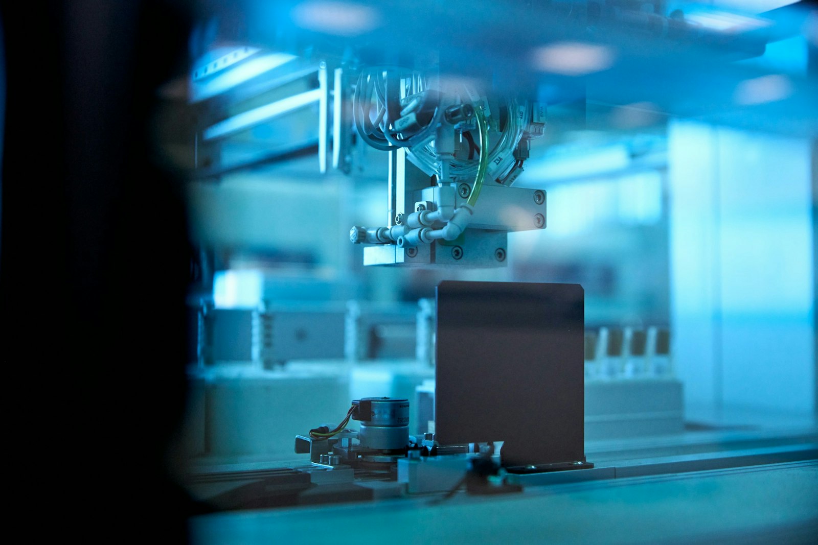 Industrial robotic arm in blue lit factory.