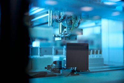 Industrial robotic arm in blue lit factory.