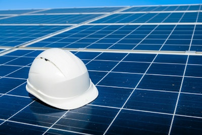 A white hard hat sitting on top of a solar panel.