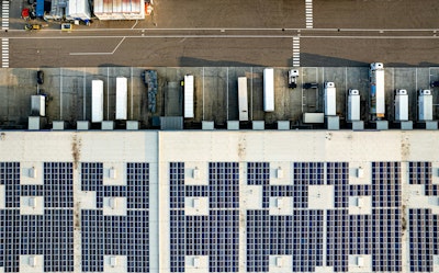 An aerial view of a parking lot with lots of solar panels.