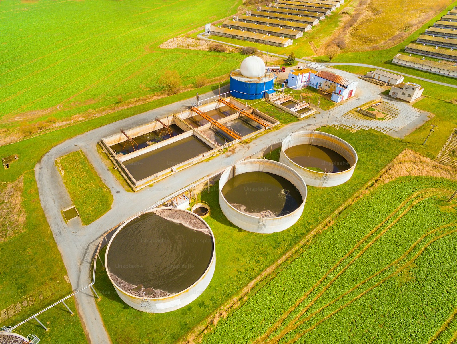 Aerial view to biogas plant from pig farm in green fields. Renewable energy from biomass. Modern agriculture in Czech Republic and European Union.