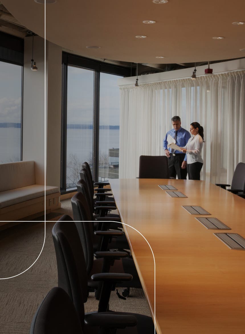 two people looking at a paper behind a conference desk