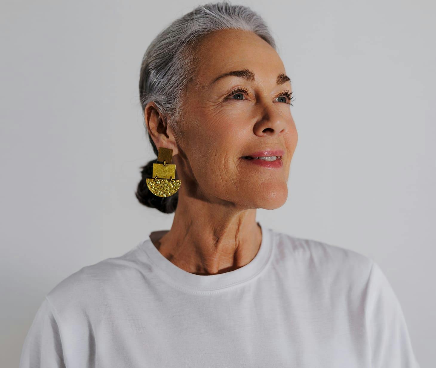 woman with grey hair wearing big gold earrings