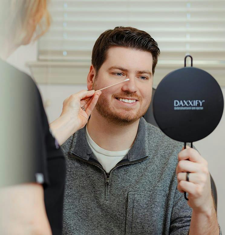 man looking at his reflection in a hand held mirror