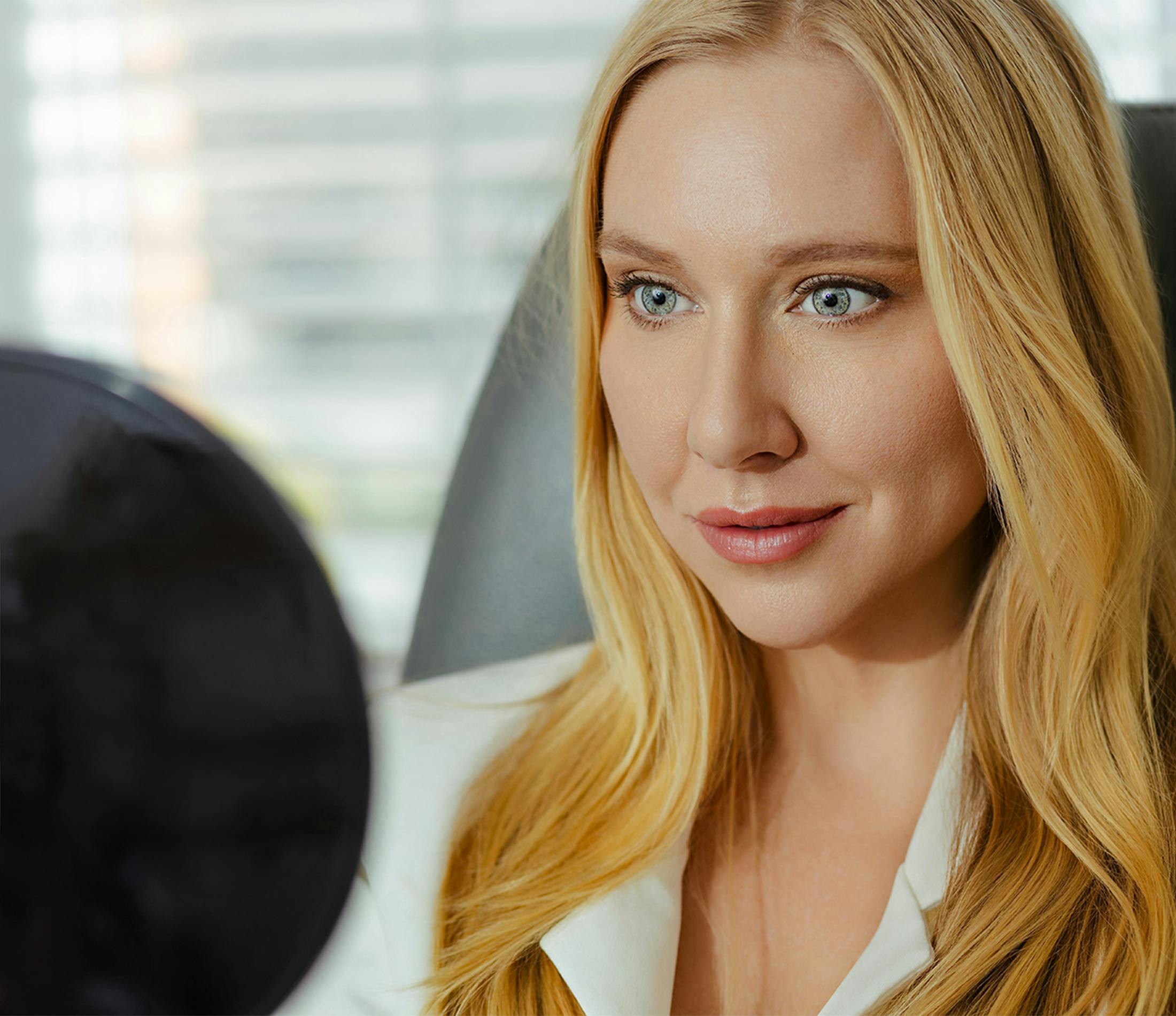 Woman with long blonde hair and blue eyes in white blazer