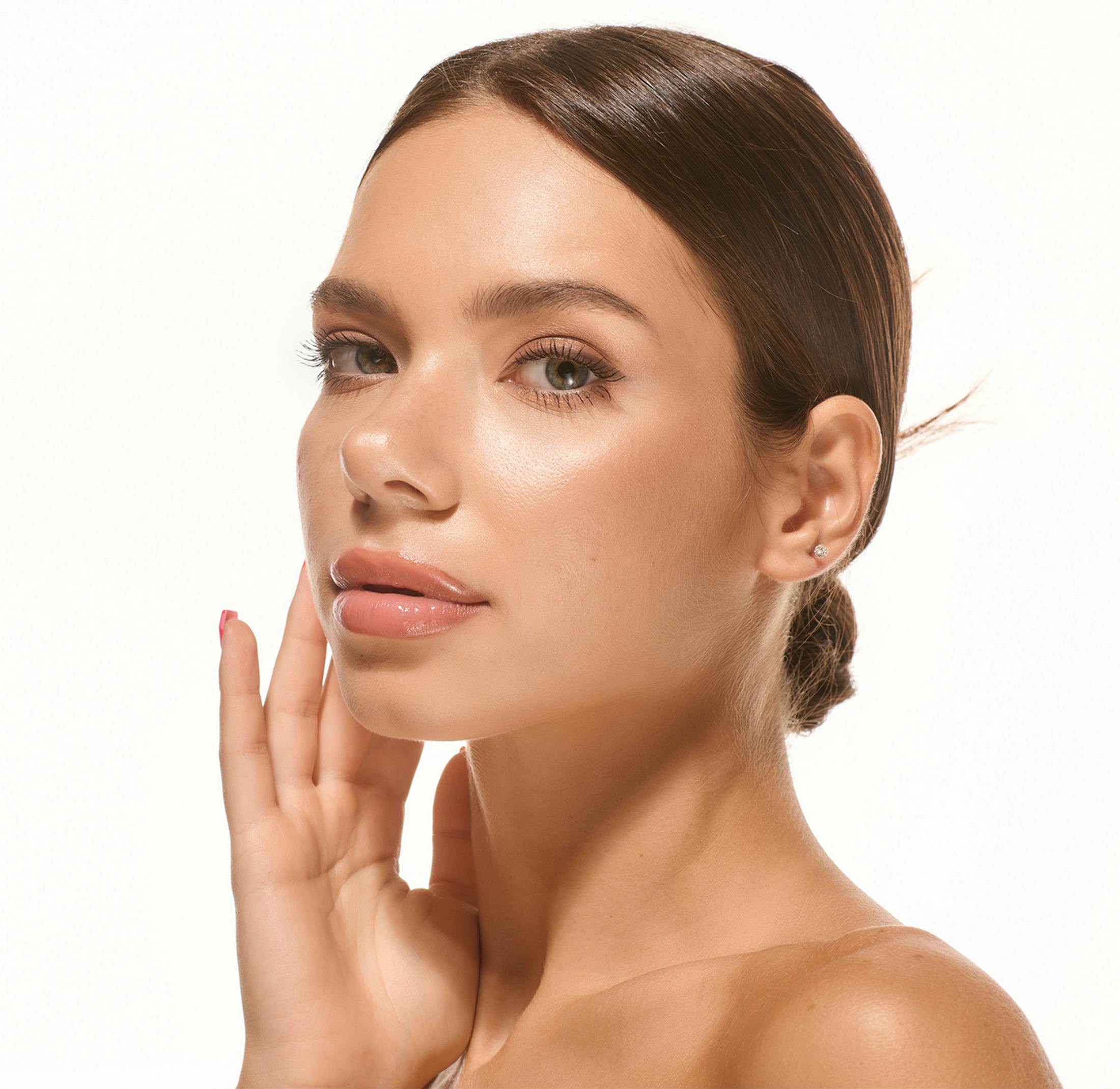 Young woman with glowing skin touching her face gently