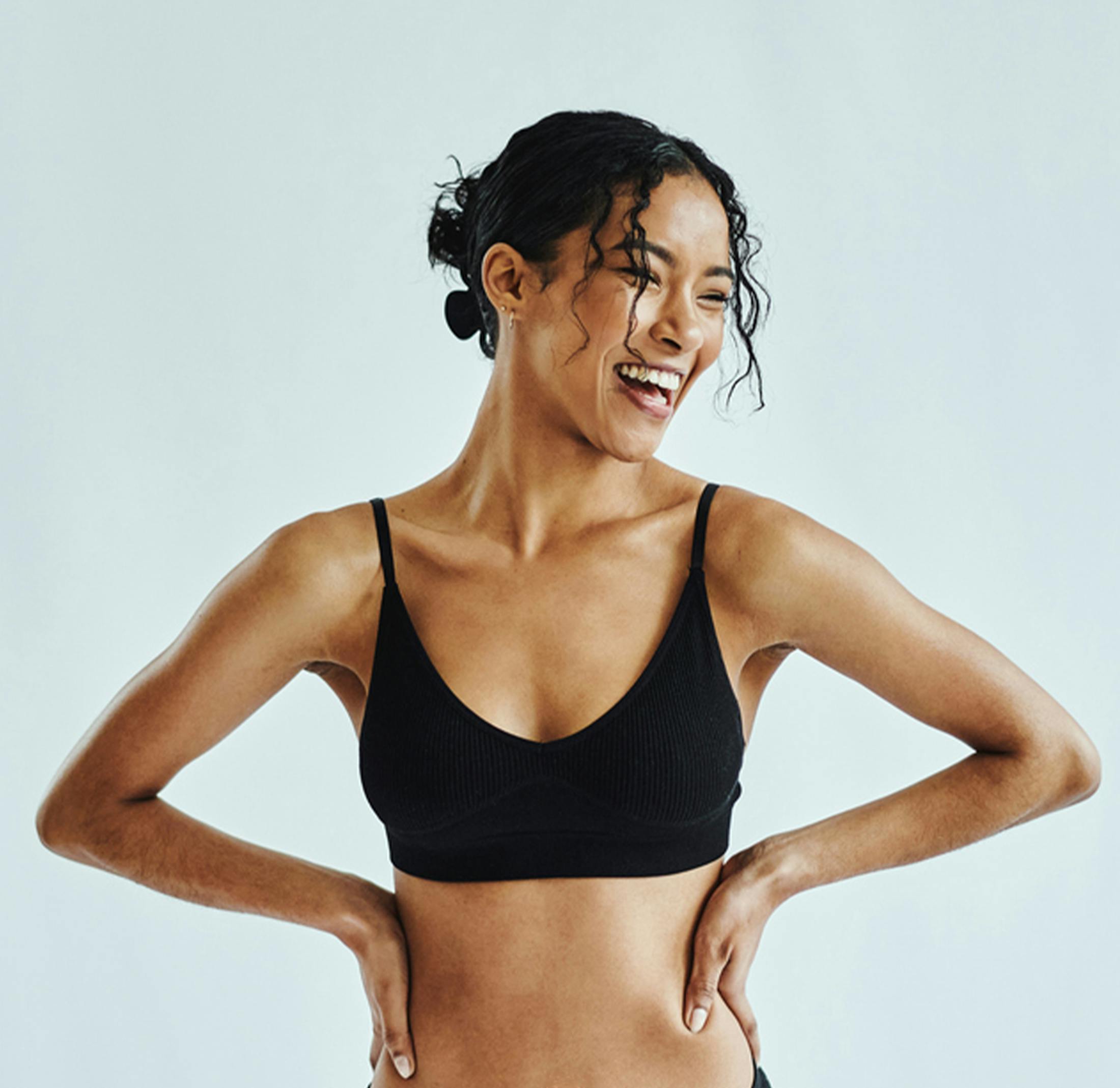 Smiling woman in black sports bra with hands on hips