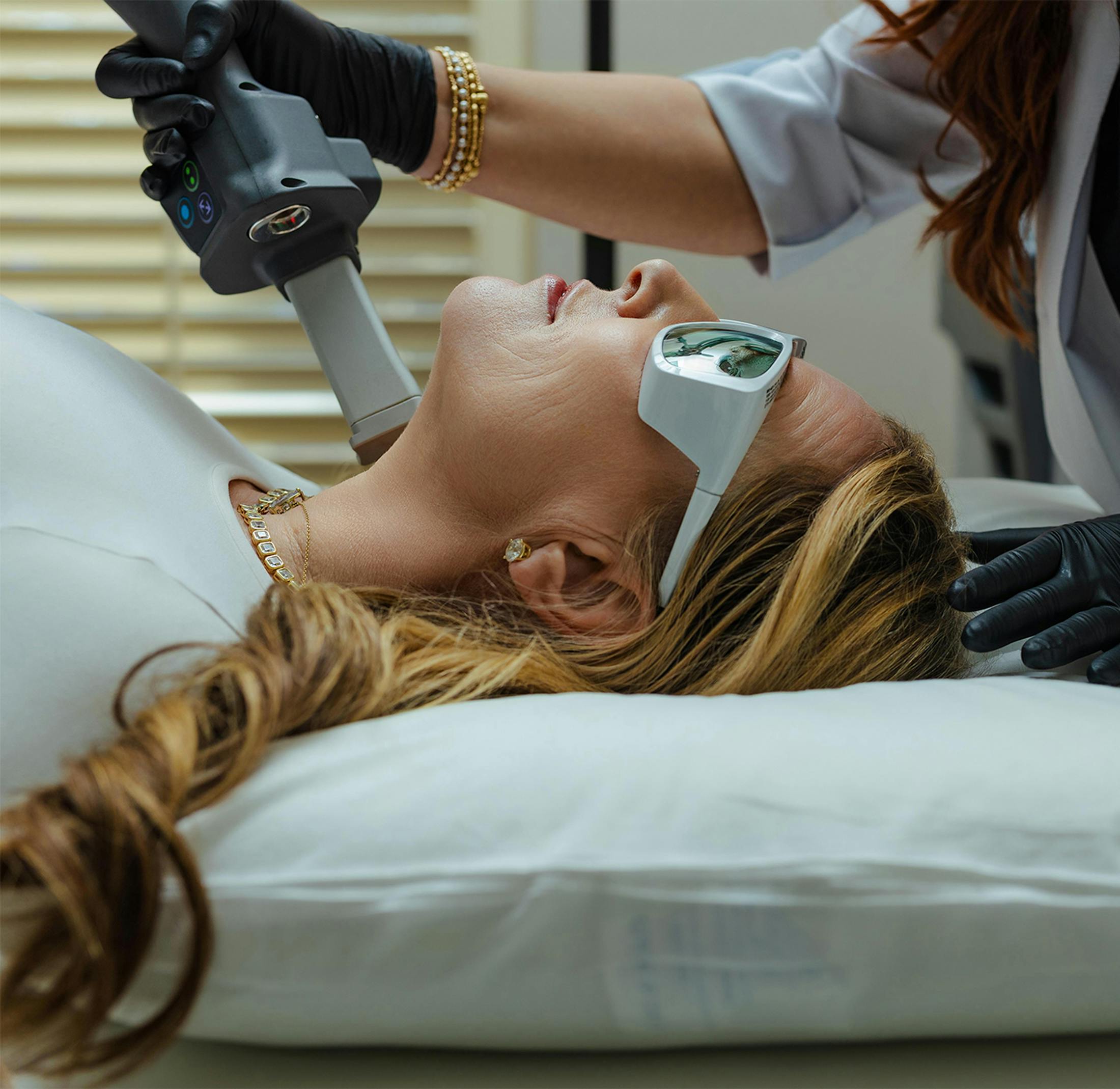 Woman receiving YAG laser facial treatment from a gloved practitioner