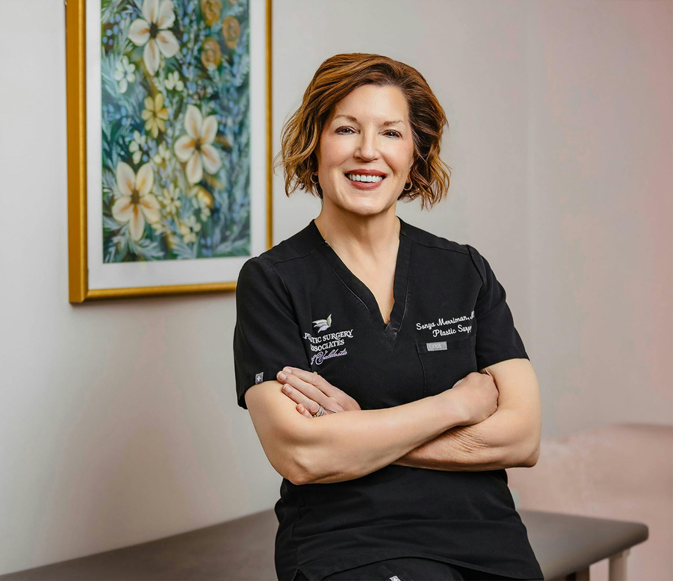 Dr. Sonya Merriman, plastic surgeon, smiling with arms crossed in scrubs