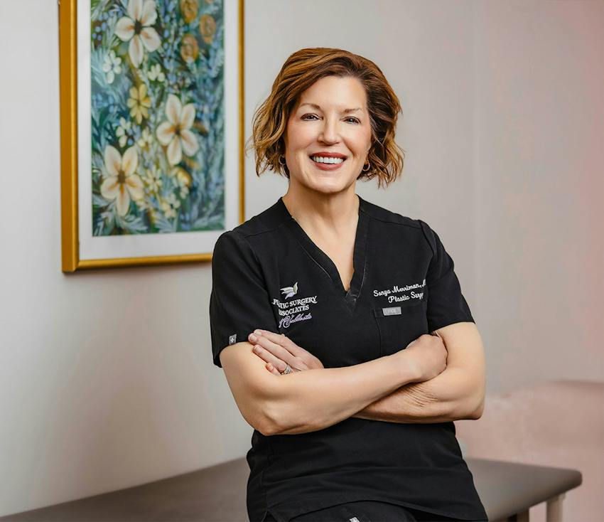 Dr. Sonya Merriman, plastic surgeon, smiling with arms crossed in scrubs