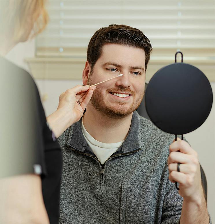 man looking at his reflection in a handheld mirror