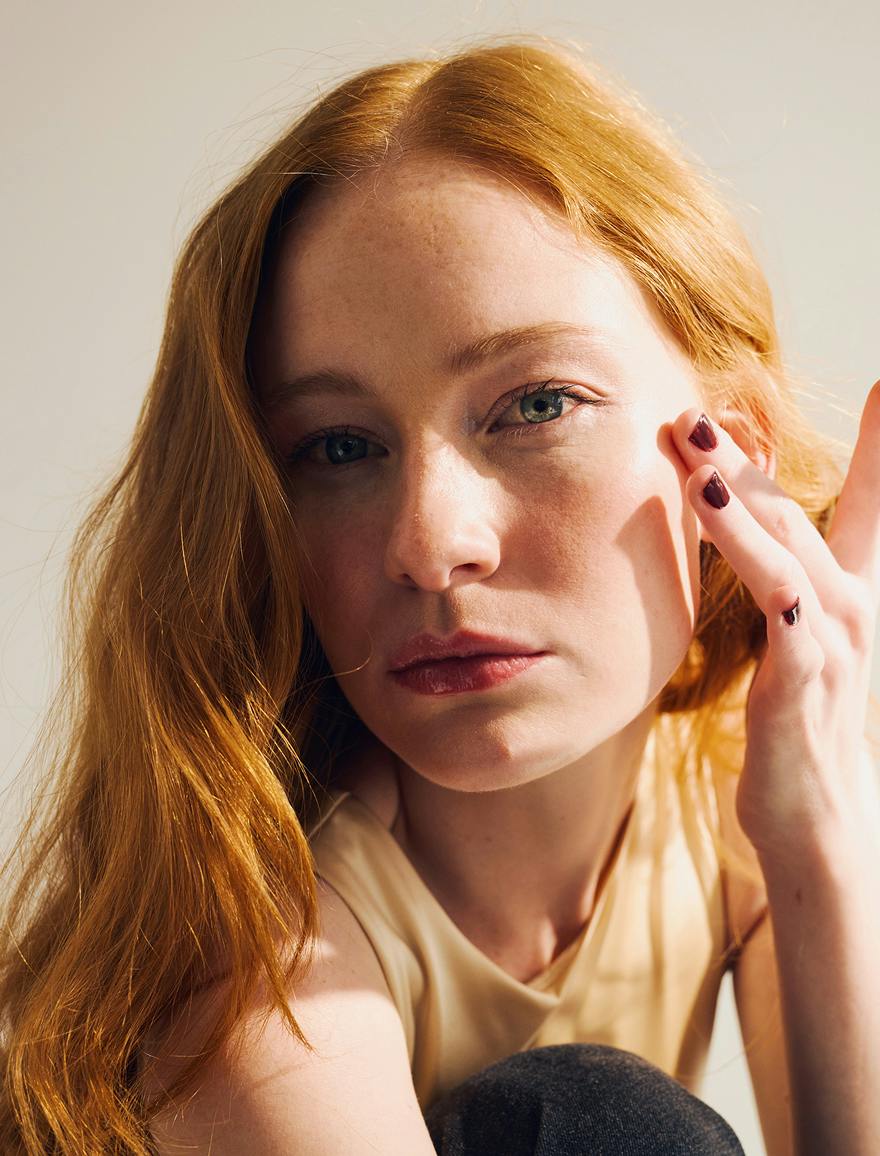 Woman with red hair resting her fingertips on her cheek