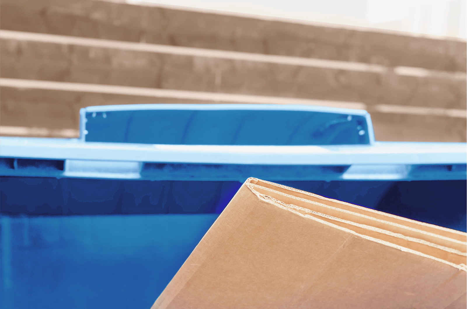 Brown cardboard sits in a plastic blue recycling bin.