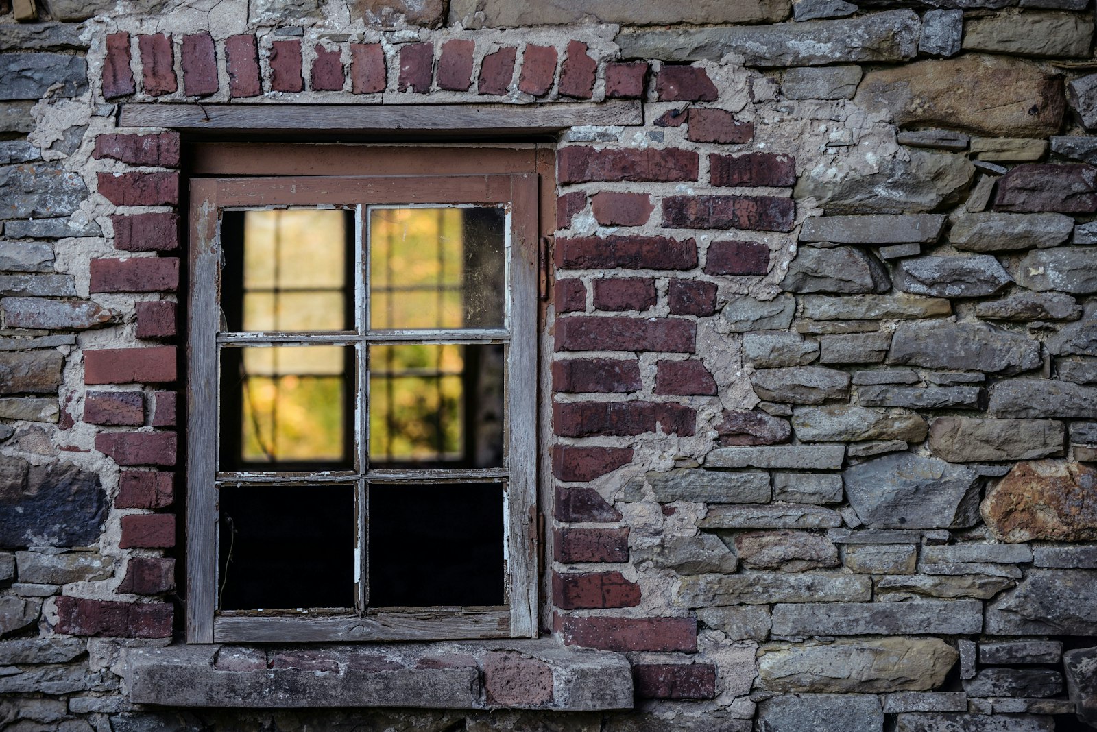 A rustic red brick wall with an old wooden window frame.