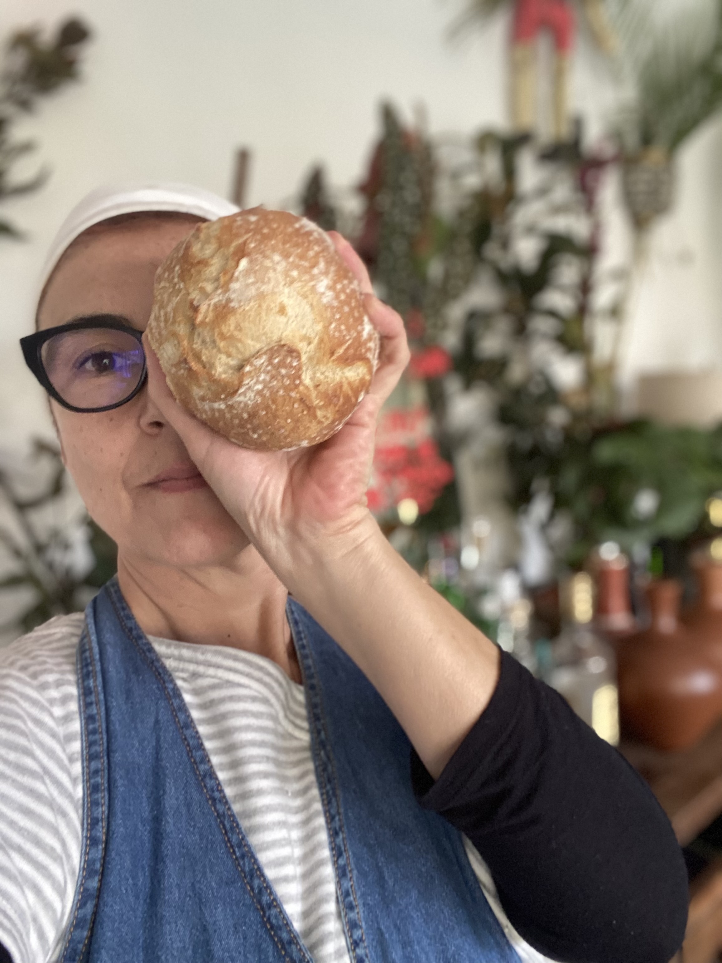 Chef Graziela Scorvo Tavares de frente para a câmera, segurando o pão em frente ao rosto