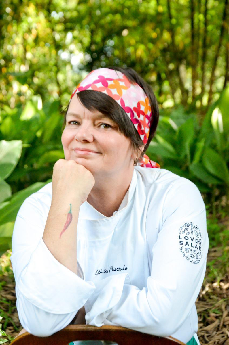 Chef Leticia Massula, aparece de frente com um lenço vermelho na cabeça.