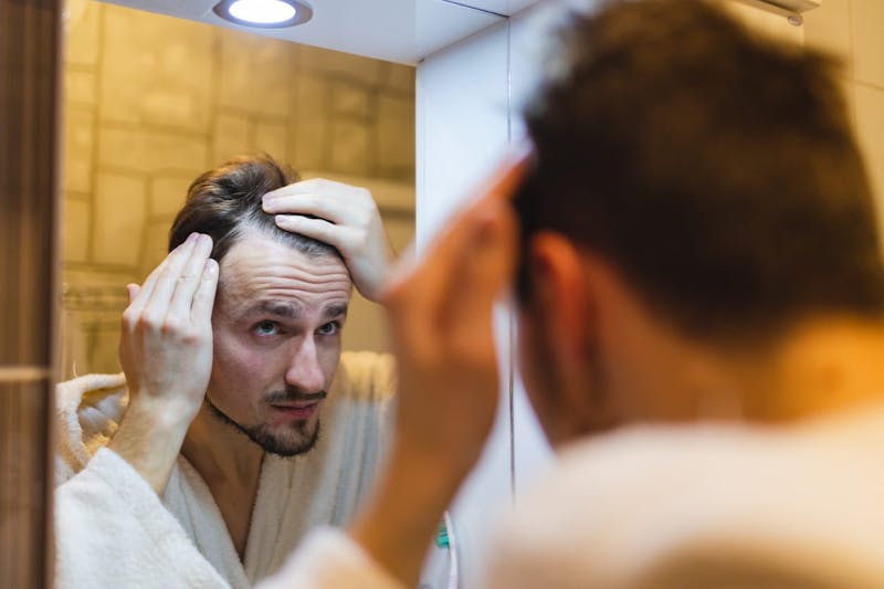 man looking at his hair in the mirror