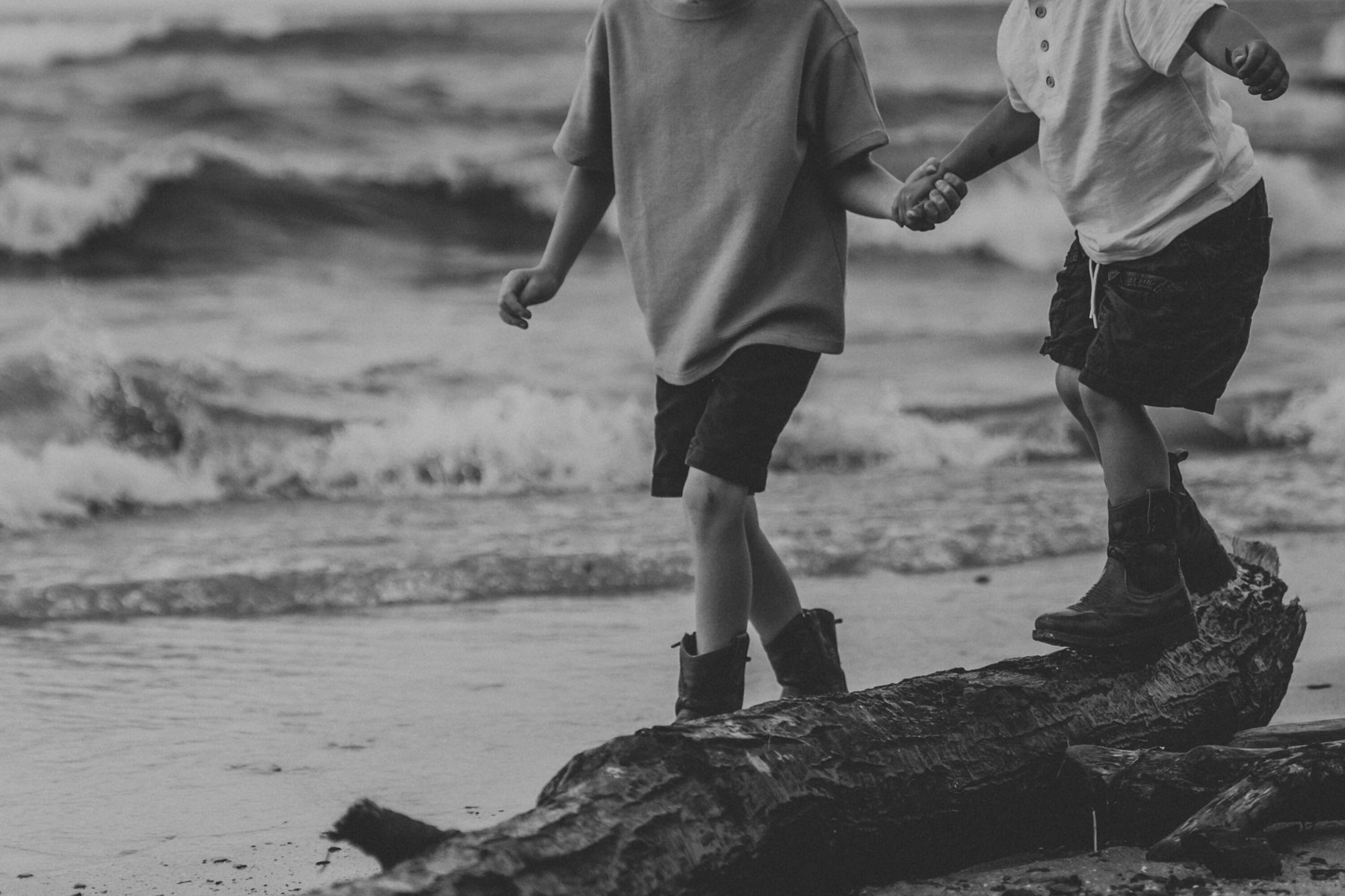 Black and white photo of kids' feet on driftwood at the Lake Erie shore at Veterans Memorial Park in Avon Lake, Ohio