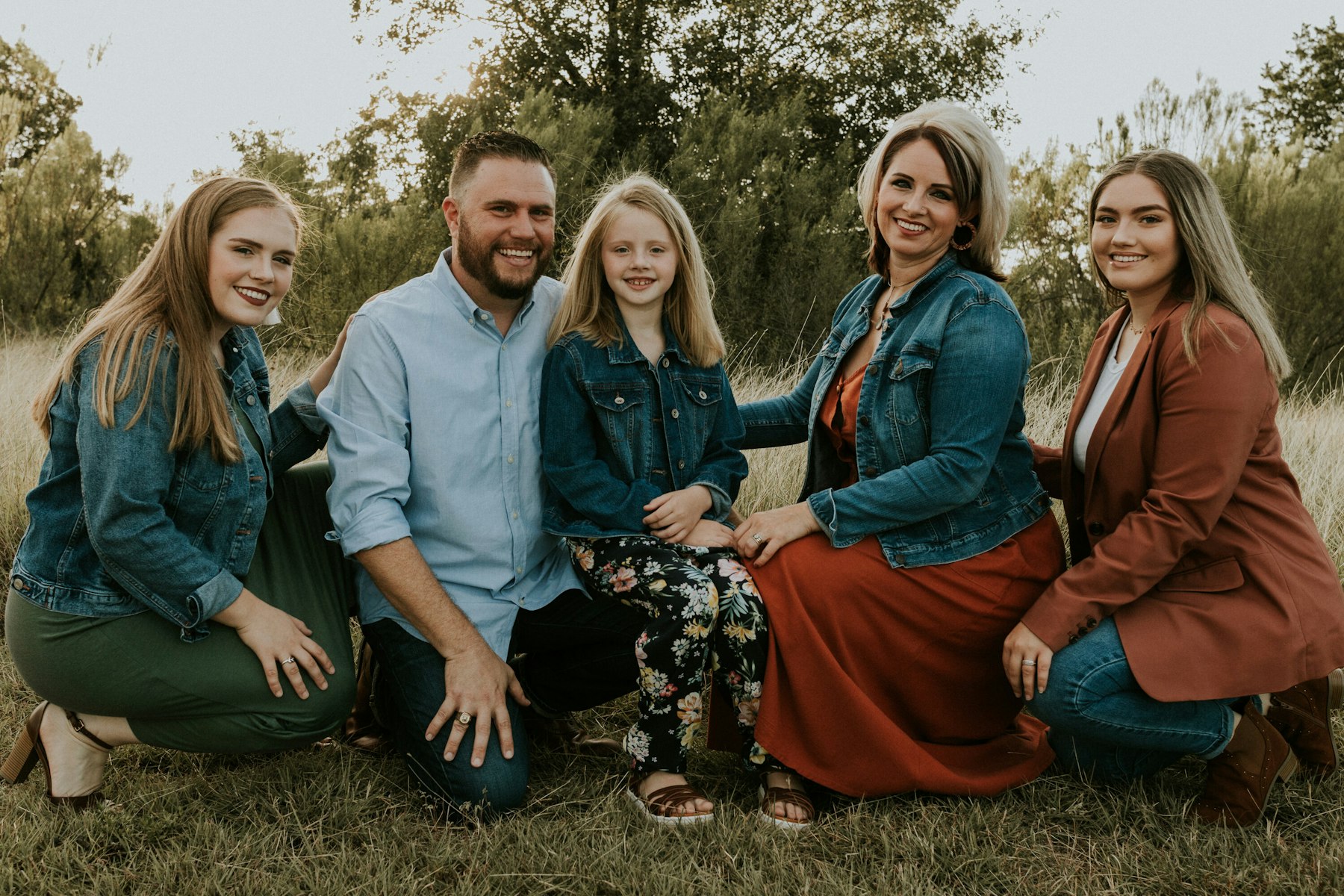 Family sitting together in tall grass during a golden hour family session