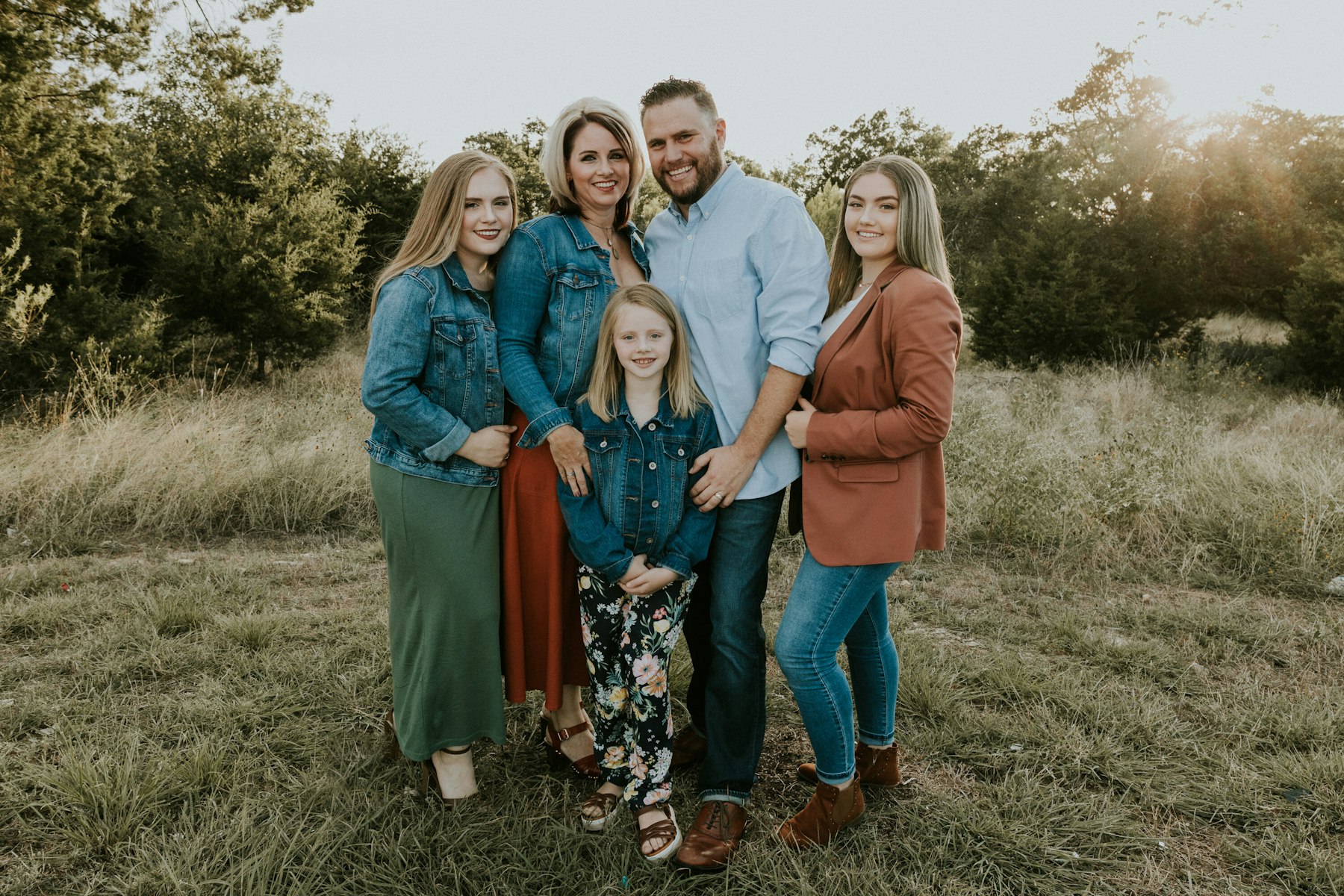 Family standing together, backlit by the setting sun during a golden hour family session