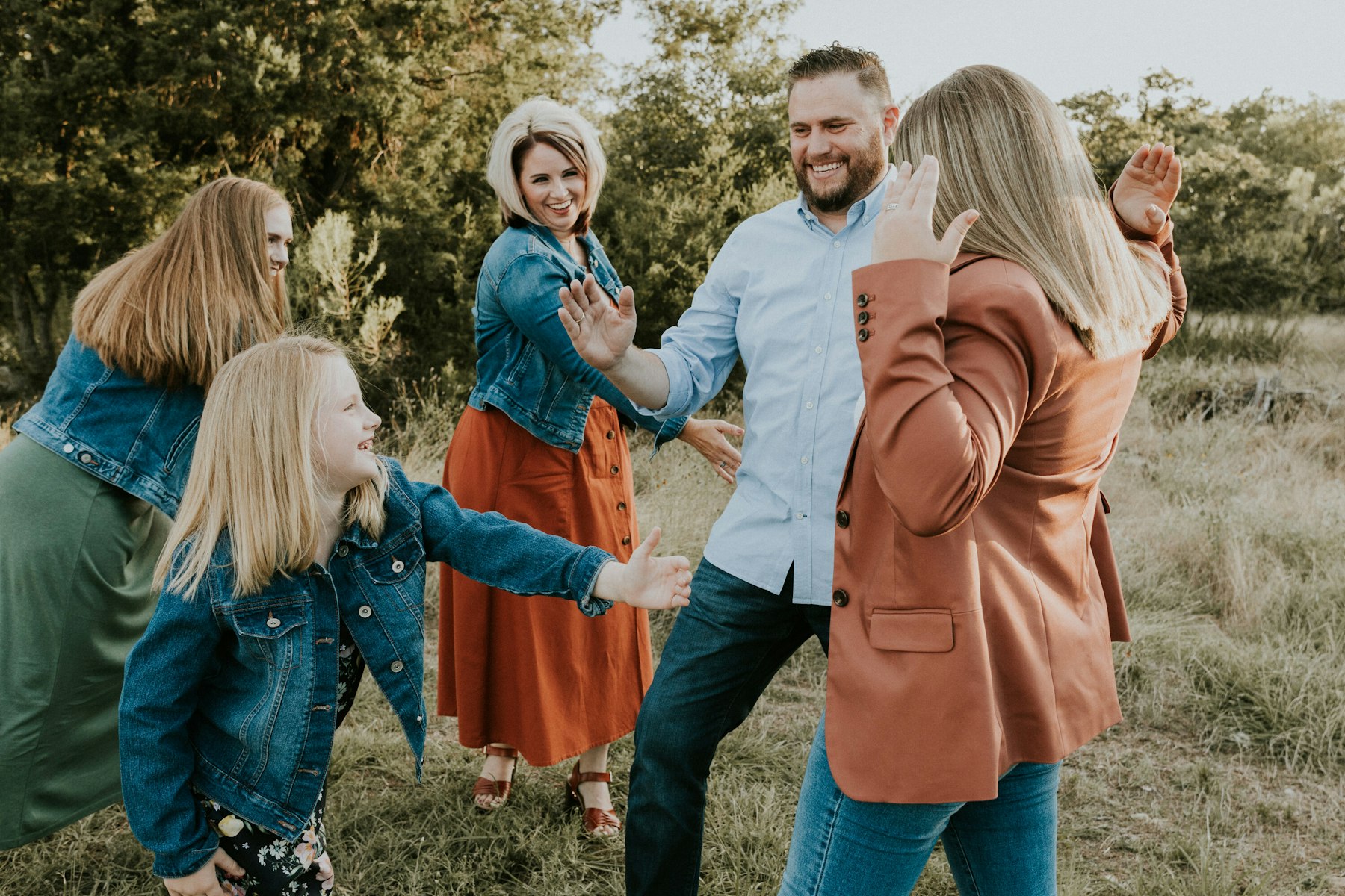 Dad playfully lifting his daughter while the family laughs during a golden hour family session