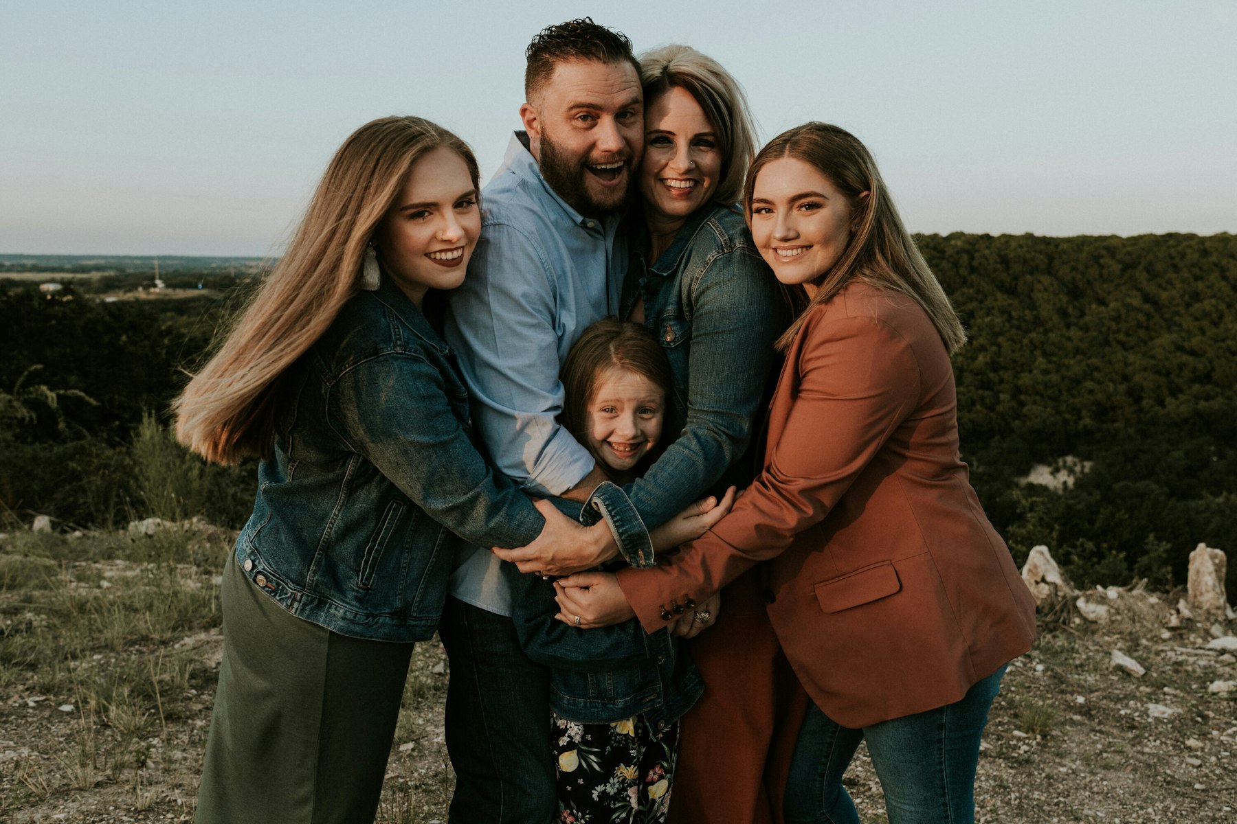 Family group hug on a hilltop during a golden hour family session