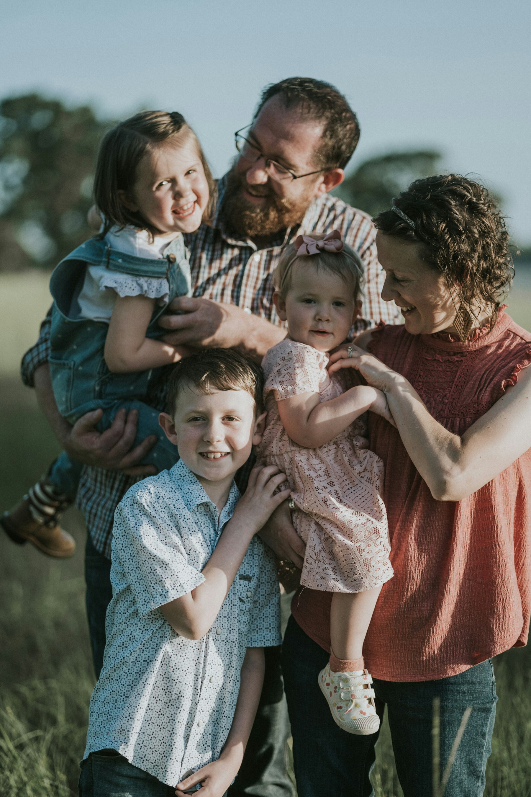 Dad holding the kids, family of five in tall grass during a summer family session in a meadow