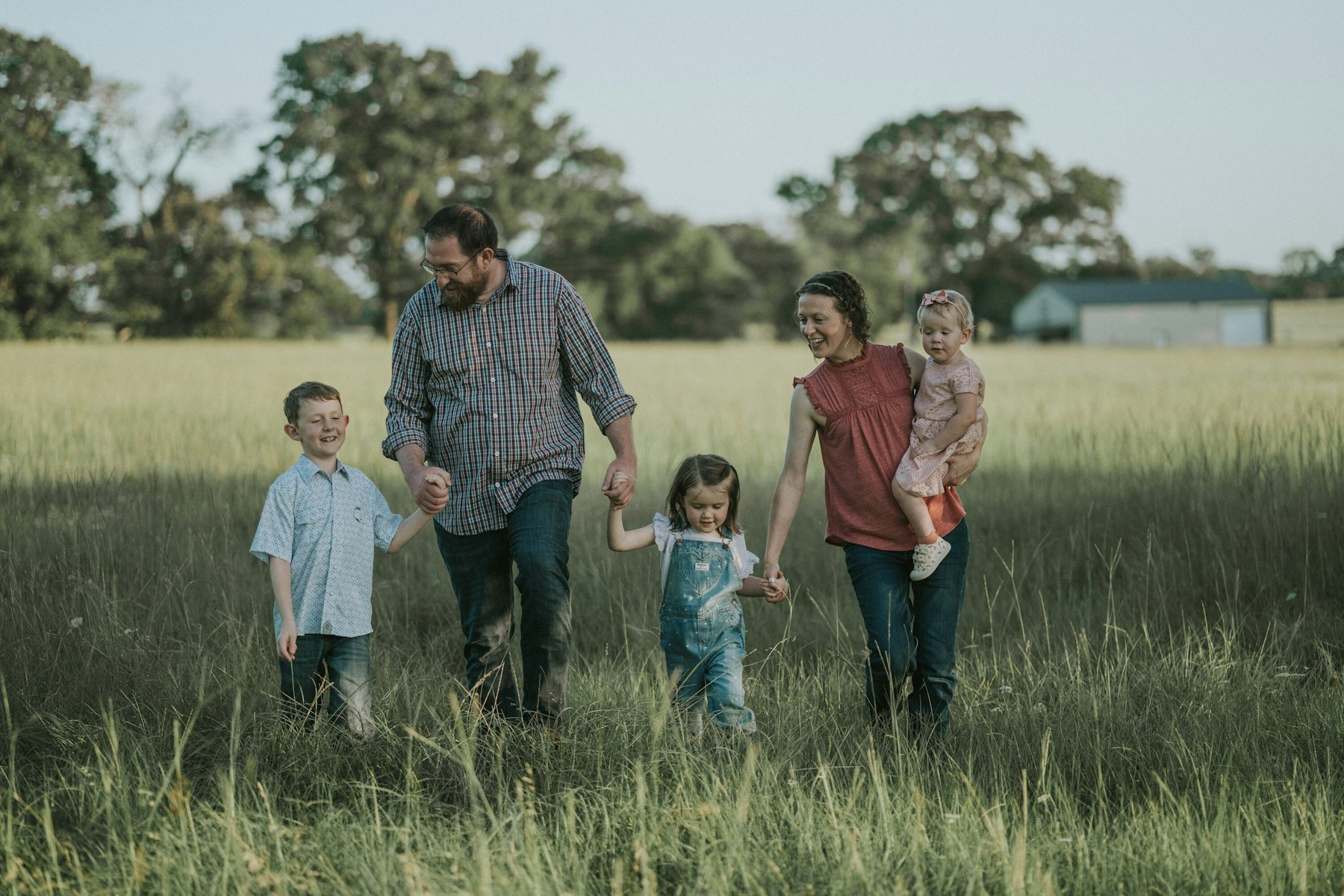 Family walking through the field in evening light during a summer family session in a meadow