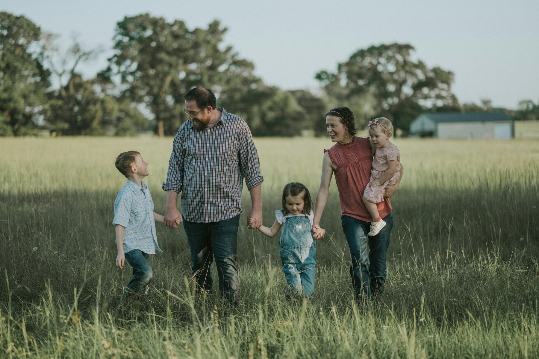 Wide view of a family strolling through the meadow during a summer family session in a meadow