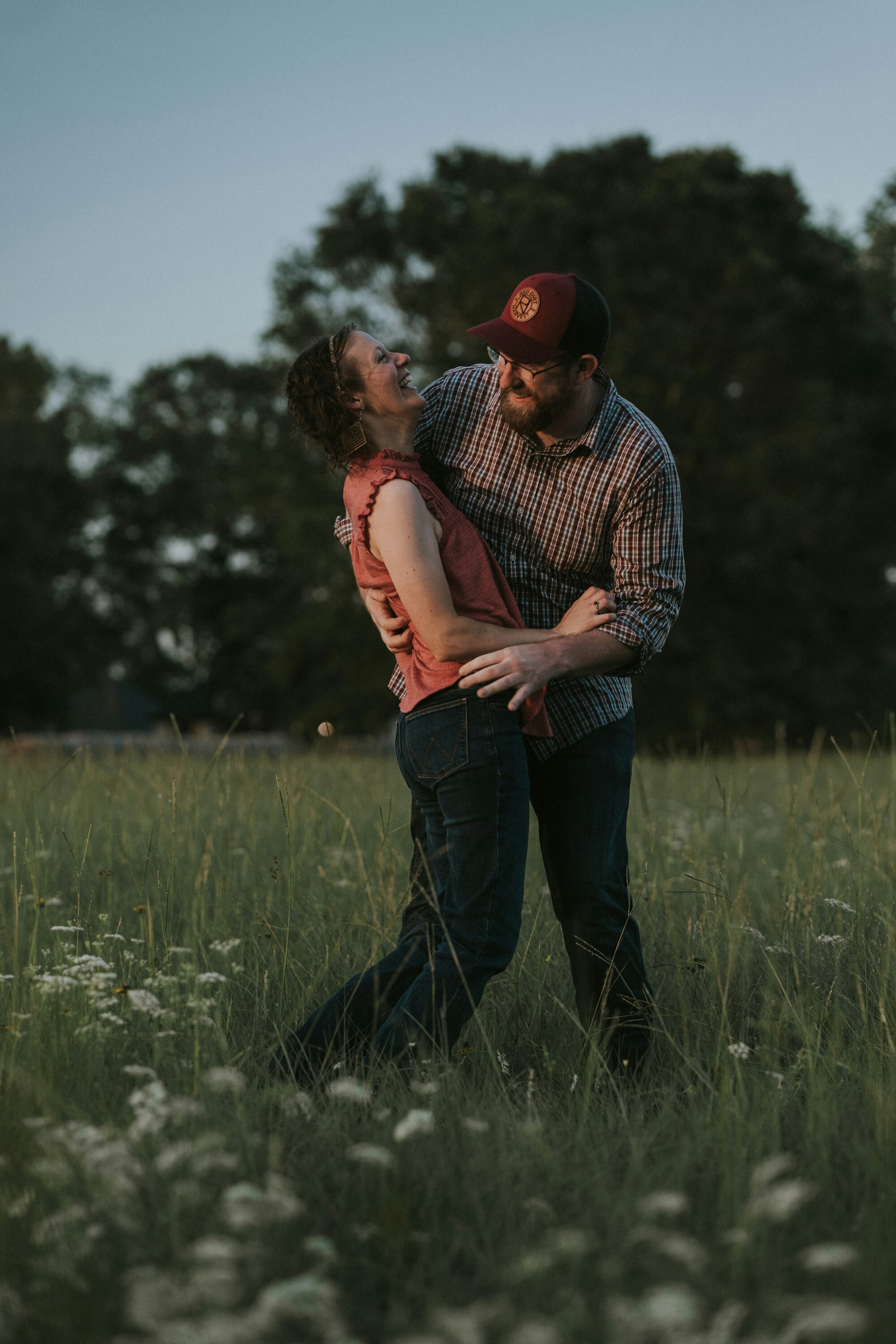 Parents embracing in the field at dusk during a summer family session in a meadow