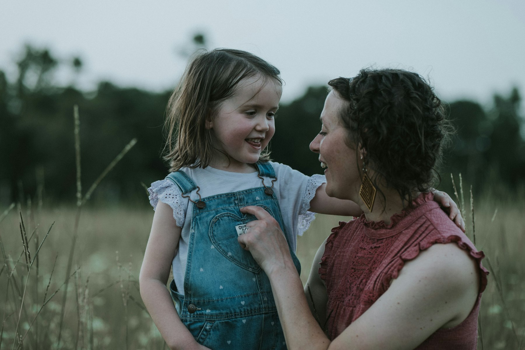 Mom and daughter laughing nose to nose during a summer family session in a meadow