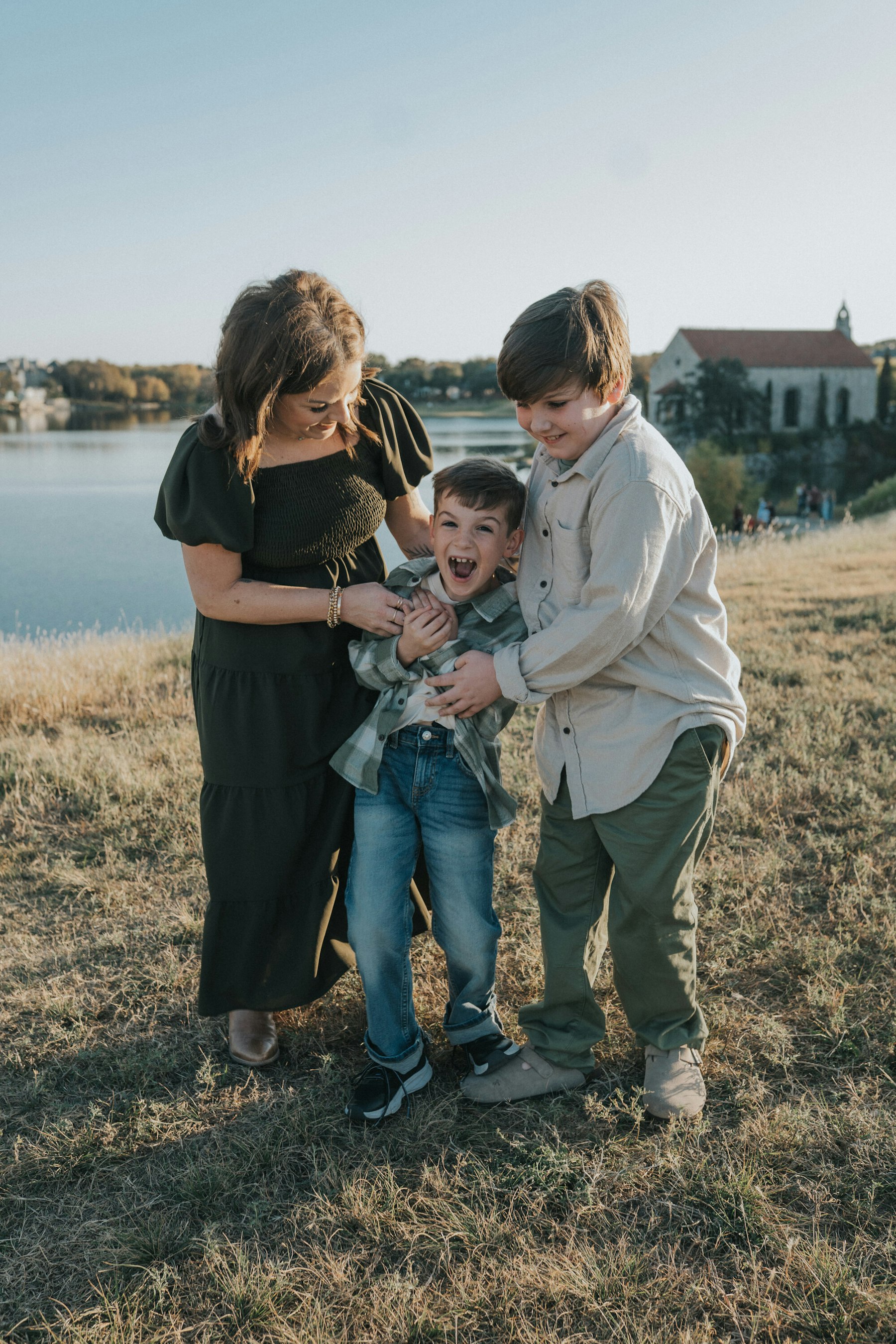 Mom tickling her two sons by the lake during a lakeside family session